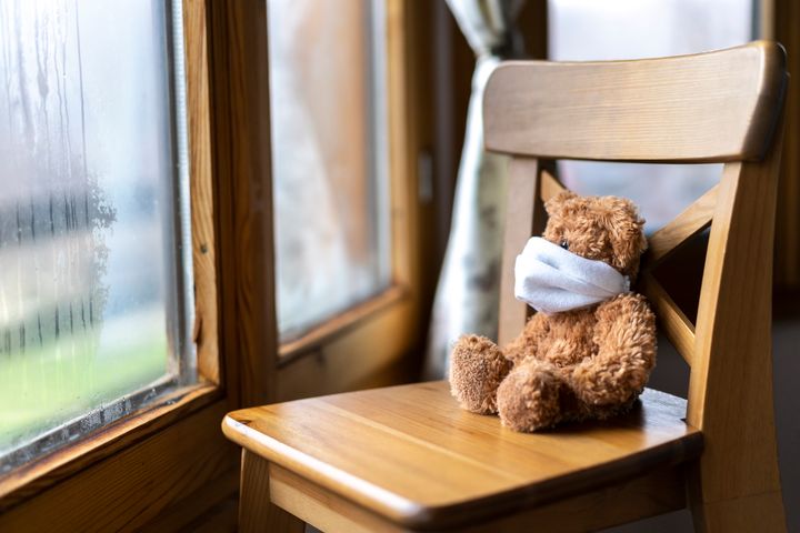 Teddy bear sitting next to window. Concept for social distancing during coronavirus pandemic