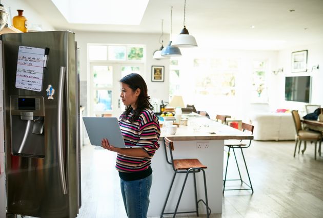 Woman at home in kitchen, checking fresh food and buying groceries online.