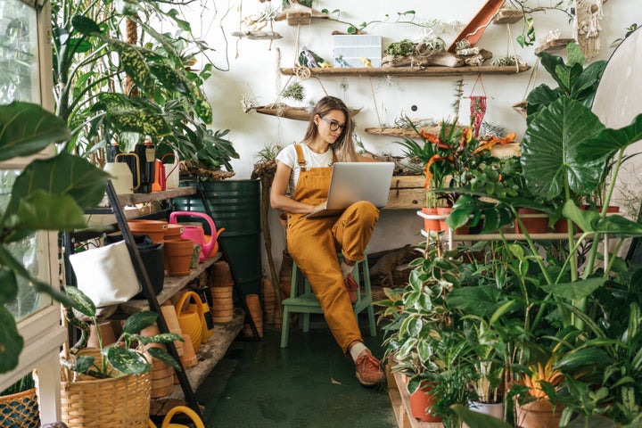 Young woman using laptop in a small gardening shop