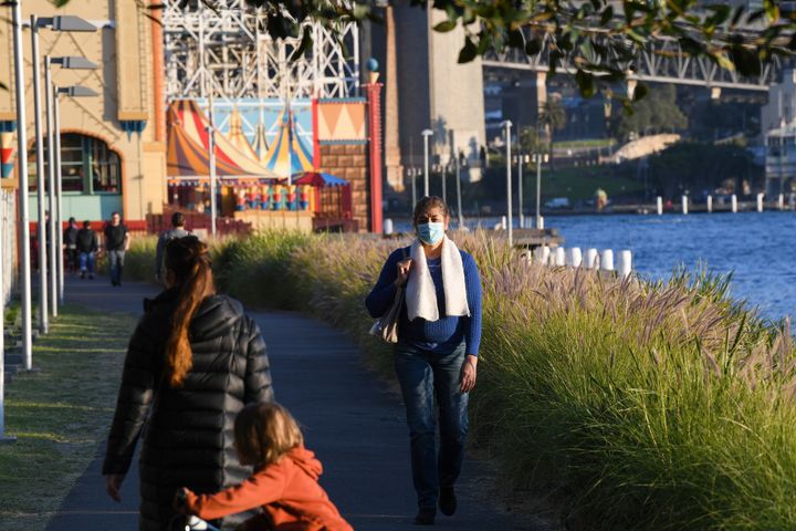 A woman wears a face mask as she walks near Luna Park beside the Harbour 