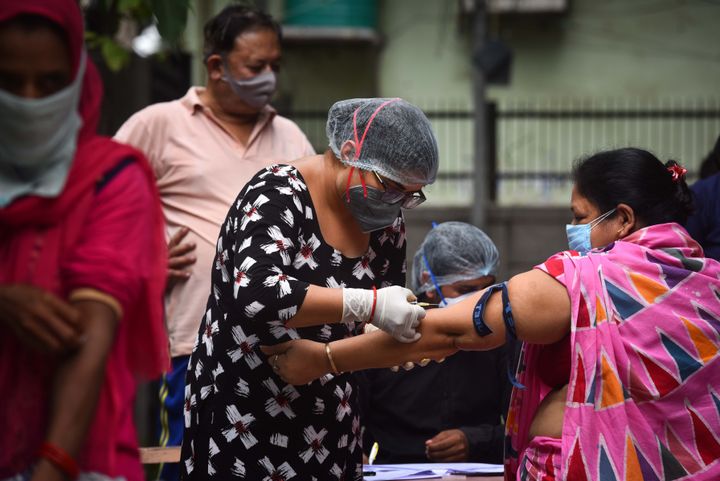 A health worker draws a blood sample from a person for use in the third round of serological survey testing for coronavirus, in Sarai Rohilla, on September 2, 2020 in New Delhi.