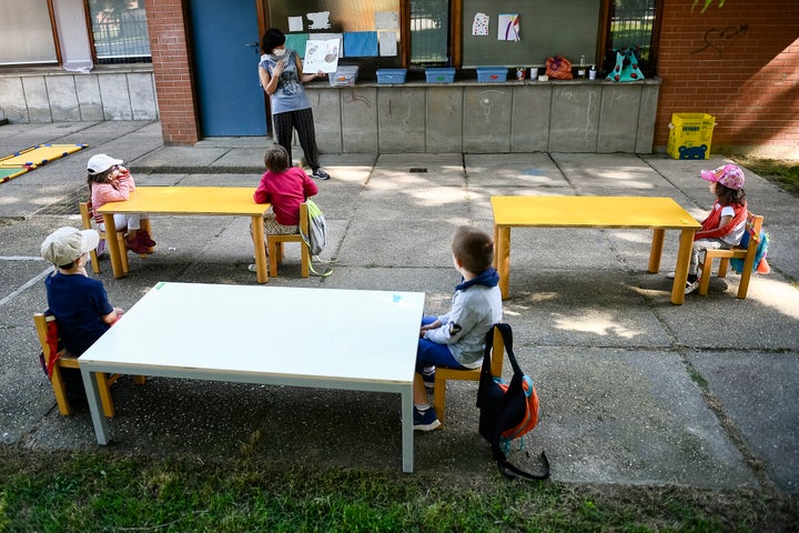 A teacher reads a book to kindergarten children in a school garden in Turin, Italy.