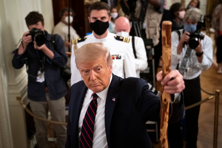 Trump holds up a walking stick given to him by Sen. Lamar Alexander (R-Tenn.) after he signed the Great American Outdoors on 