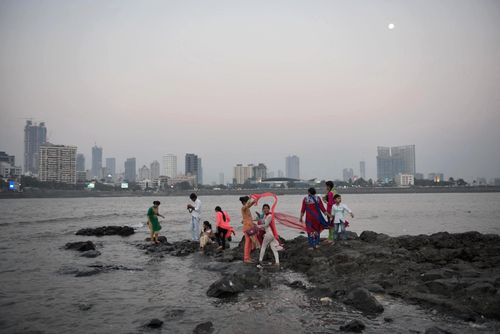 People on the rocks by the Haji Ali Dargah mosque in Mumbai. Built on an islet in 1431 to house the shroud of Pir Haji Ali Shah Bukhari, the mosque normally hosts more than 100,000 visitors each week. However, with the ongoing coastal road construction around the mosque, a large portion of the rocky bed surrounding the mosque is submerged and likely to sink further. Above: Feb. 9, 2017 | Below: July 29, 2020