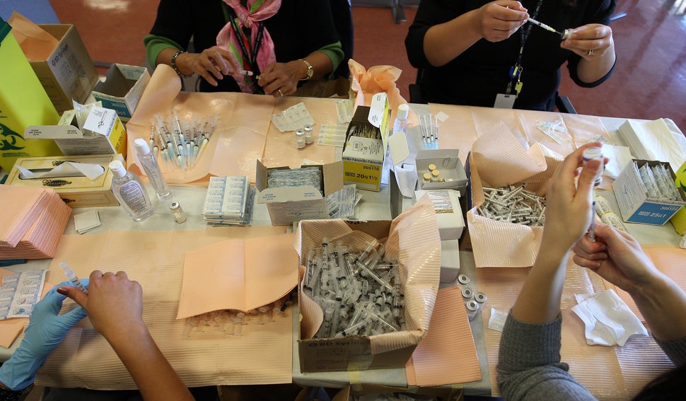 Staff preload syringes as they prepare to perform vaccinations. There was no line up to be found, just a pair of nurses handi