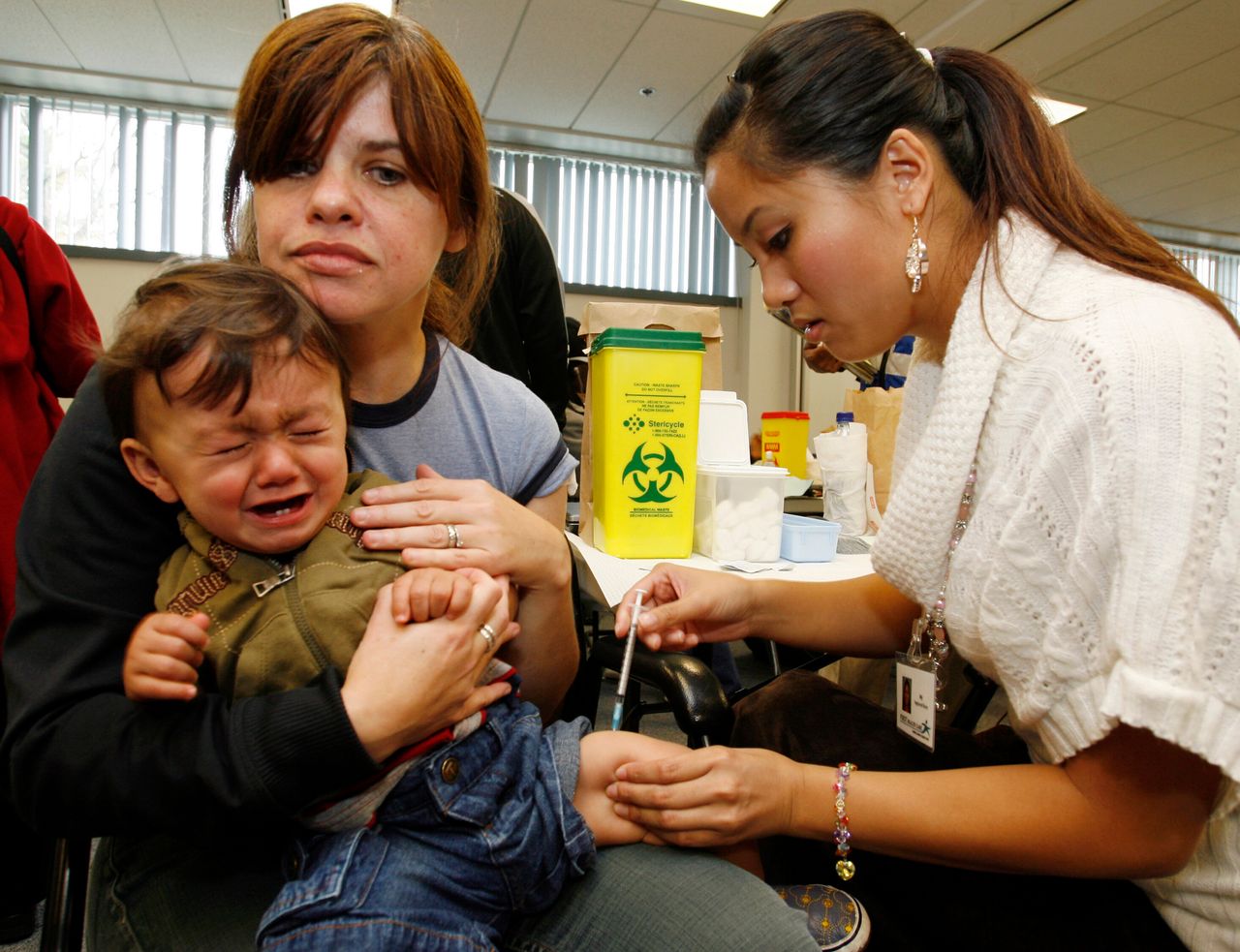Patricia Steward holds her 11-month son Brayden as he receives his H1N1 pandemic vaccine from a nurse at the The East York Civic Centre clinic in Toronto October 29, 2009. REUTERS/Mike Cassese (CANADA HEALTH)