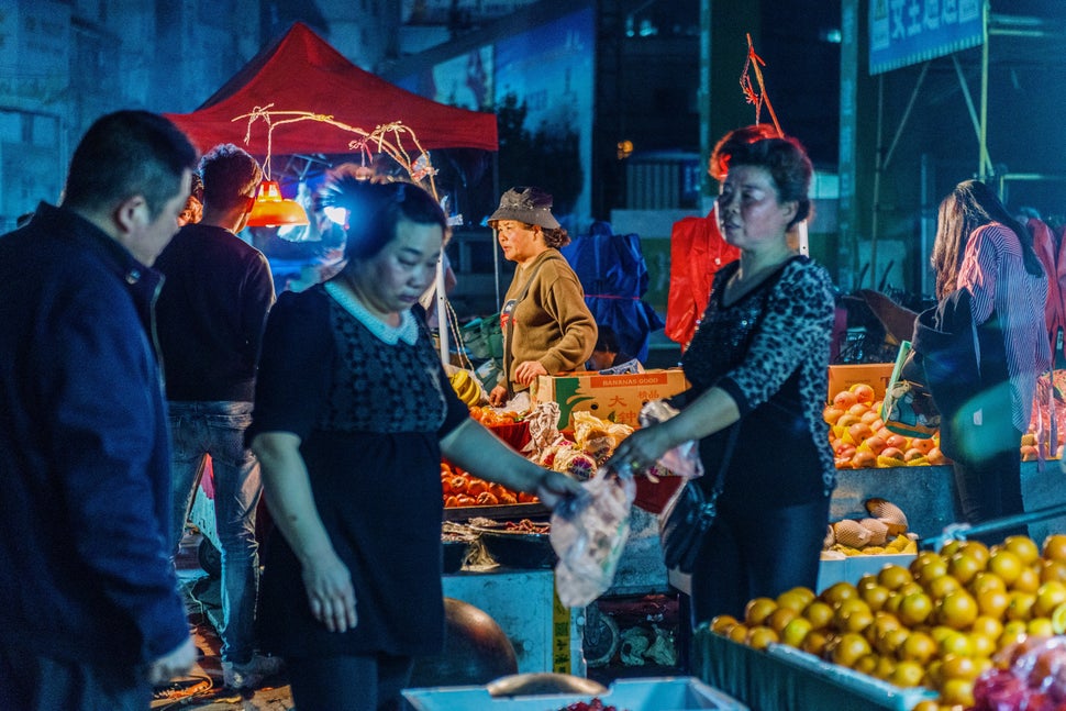 Meat and produce vendors work at a village market in Wuhan, China. At its peak, more than 100,000 migrant workers lived in the village. About 65% of the migrant workers decided not to come back to the village after the COVID-19 outbreak. Sales in the market have been negatively impacted. Above: March 22, 2019 | Below: July 31, 2020