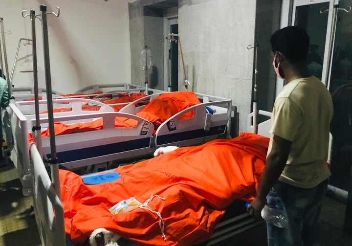 A man stands by the bodies of victims of a gas pipeline explosion at a hospital in Dhaka, Bangladesh, Saturday, Sept. 5, 2020