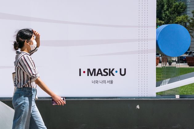 A citizen passes by a recommended sculpture to wear a mask installed in front of Seoul City Hall.  Year 2020