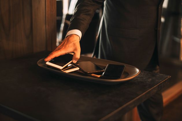 Midsection of male lawyer keeping smart phone on tray in