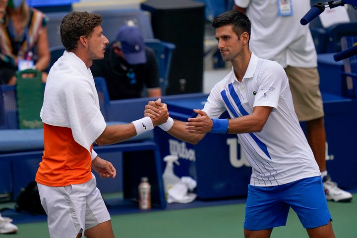 Djokovic shakes hands with Pablo Carreno Busta after defaulting the match.
