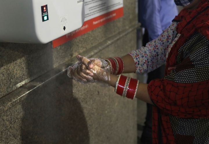 A woman sanitizes her hand at Delhi Metro station before boarding the train in Gurugram on the outskirts of New Delhi, India, Monday, September 7, 2020. 