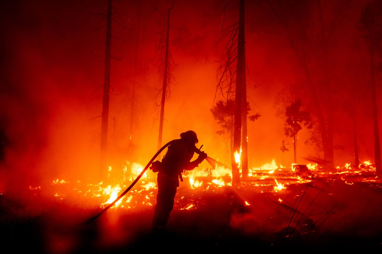 A firefighter battles the Creek Fire as it threatens homes in the Cascadel Woods neighborhood of Madera County, California on Monday.