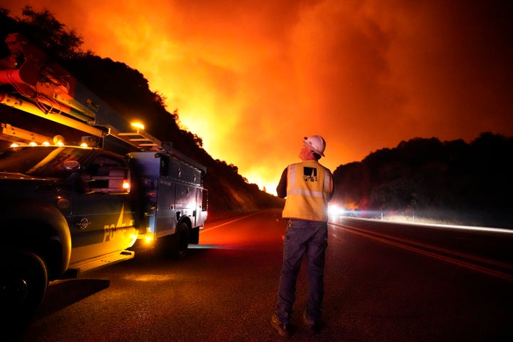 A Pacific Gas and Electric worker looks up at the advancing Creek Fire along Highway 168 Tuesday, Sept. 8, 2020, near Alder Springs, Calif. (AP Photo/Marcio Jose Sanchez)