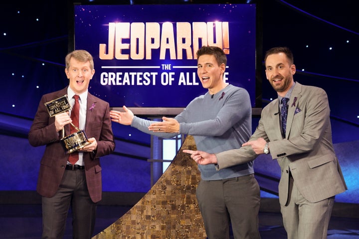 Ken Jennings holds his “G.O.A.T.” trophy next to fellow contestants James Holzhauer and Brad Rutter.