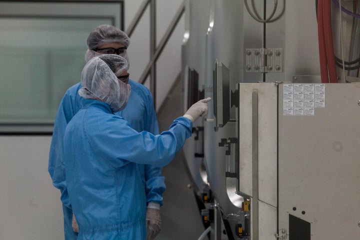 Laboratory workers wearing PPE check a screen of a centrifuge machine at the production plant of mAbxience biotechnology company on August 13, 2020 in Garín, Argentina. The Argentina lab, property of Grupo Insud, will co-manufacture with Mexico the coronavirus vaccine created by Oxford University and Swedish-British pharmaceutical firm AstraZeneca. 