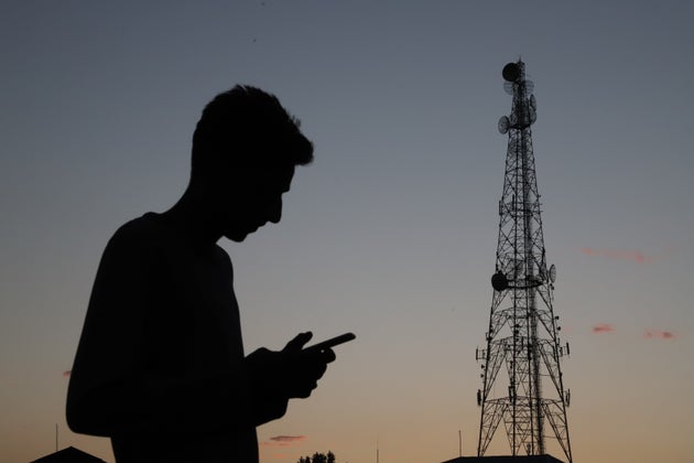 Mobile Phone towers are seen as a boy uses a Cell Phone in Sopore town of District Baramulla, Jammu and...