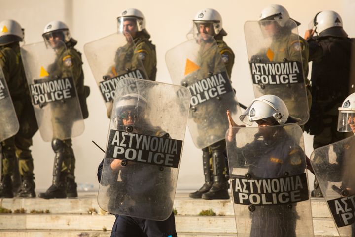Athens, Greece - April 16, 2015: Riot police with their shield, take cover during a rally in front of Athens University, which is under occupation by protesters leftist and anarchist groups.
