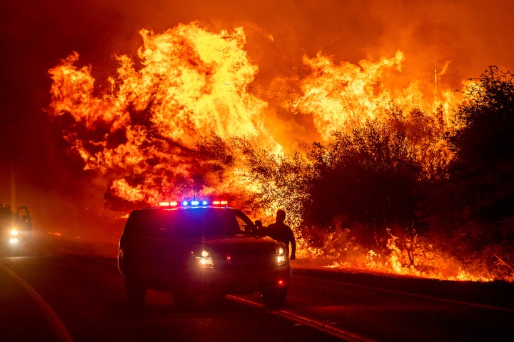 Flames lick above vehicles on Highway 162 as the Bear Fire burns in Oroville, Calif., on Wednesday, Sept. 9, 2020. (AP Photo/Noah Berger)