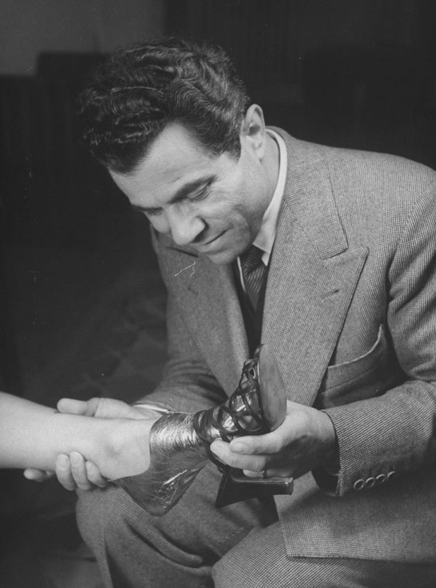 Ο σχεδιαστής Σαλβατόρε Φεραγκάμο δοκιμάζει μια γόβα στο πόδι πελάτισσάς του που το έχει τυλίξει με προστατευτική μεμβράνη. 