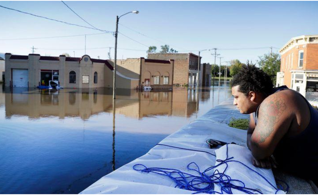 Appuyé sur un mur anti-inondation, Cory Harrison observe les commerces de Cedar Rapids inondés le 27 septembre 2016. La ville a érigé en urgence un système de barrières Hesco sur plus de 15 kilomètres pour aider à contenir la crue.