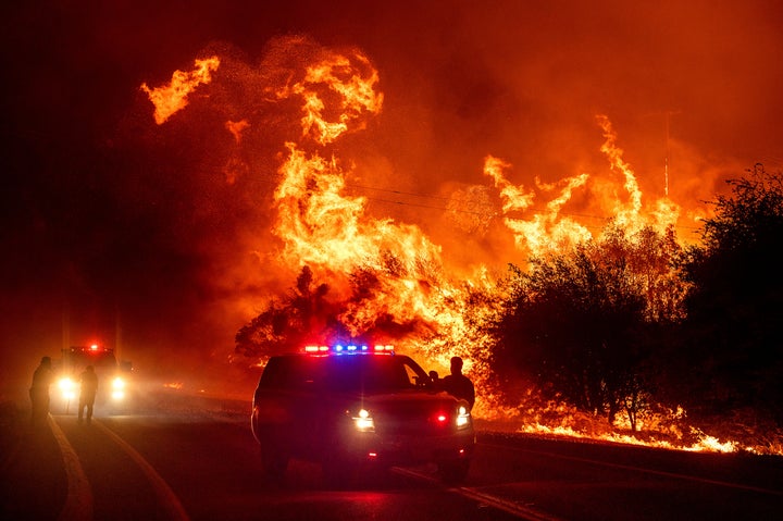 Flames lick above vehicles on Highway 162 as the Bear Fire burns in Oroville, Calif., on Wednesday, Sept. 9, 2020. The blaze, part of the lightning-sparked North Complex, expanded at a critical rate of spread as winds buffeted the region. (AP Photo/Noah Berger)