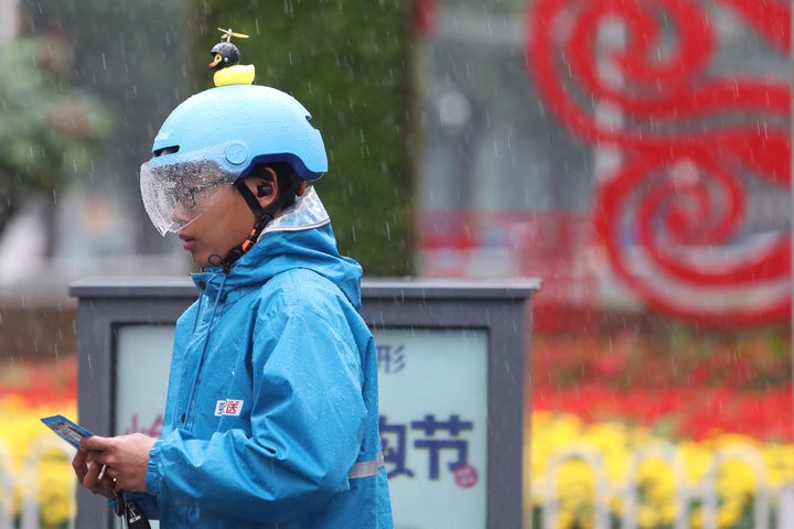 雨の中配送する 餓了麼（ウーラマ）の配送員。青い制服が特徴。餓了麼は中国語で「お腹すいた？」という意味 (Photo by Yang Zheng/VCG via Getty Images)