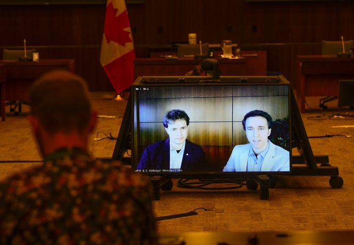 Marc Kielburger, screen left, and Craig Kielburger, screen right, appear as witnesses via videoconference during a House of Commons finance committee in the Wellington Building in Ottawa on July 28, 2020.