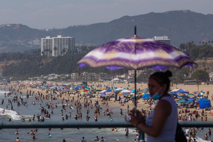 A woman uses an umbrella to protect herself from the sun at Santa Monica pier while people flocked to the beach amid a heat wave on Sept. 6, 2020.