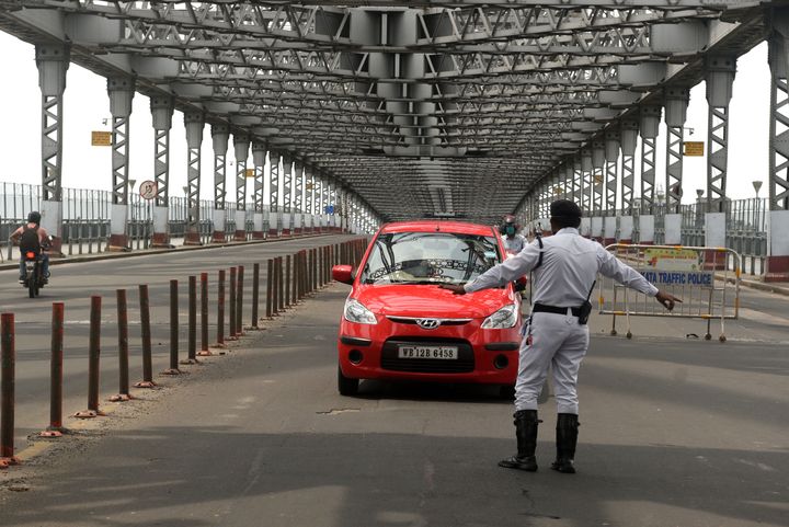 A Kolkata police personnel stops a car on Howrah Bridge amid a weekly complete lockdown imposed by the West Bengal government on September 7, 2020 in Kolkata.