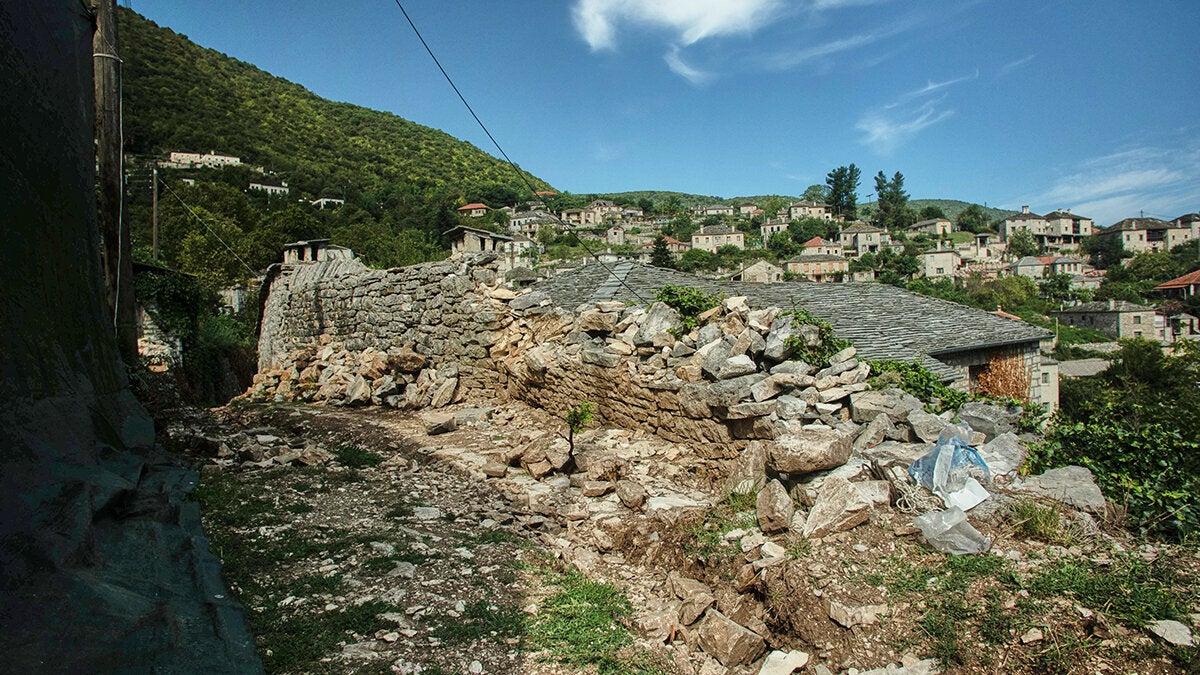 Ο τοίχος αντιστήριξης πριν αποκατασταθεί. Κάτω από αυτόν διακρίνονται τα ίχνη του παλιού καλντεριμιού.