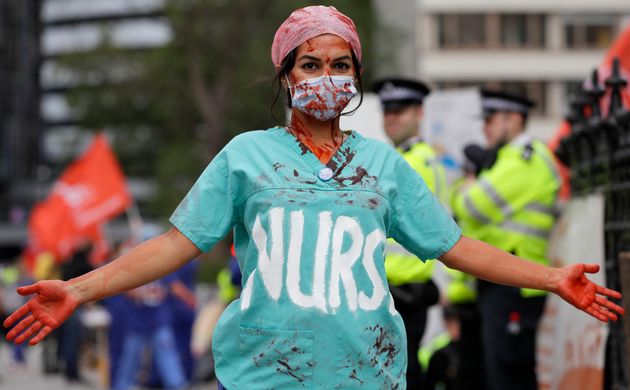 A nurse covered in fake blood takes part in a demonstration of NHS workers at hospitals across London to demand a 15 per cent pay rise by the government in London, Wednesday, Aug. 26, 2020.(AP Photo/Kirsty Wigglesworth)