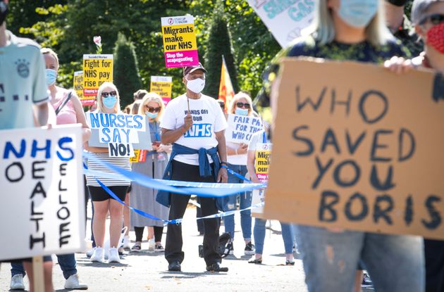 National Health Service (NHS) workers pose with placards, during a socially distanced demonstration as part of a national protest over pay, in Glasgow, Scotland, Saturday Aug. 8, 2020.  Nationwide protests on Saturday are calling for government to address what they claim is many years of reduced wages, and are calling for a voice in plans for public sector pay increases. (Jane Barlow/PA via AP)