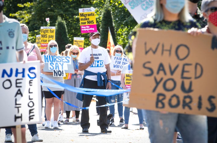 National Health Service (NHS) workers pose with placards, during a socially distanced demonstration as part of a national protest over pay, in Glasgow, Scotland, Saturday Aug. 8, 2020. Nationwide protests on Saturday are calling for government to address what they claim is many years of reduced wages, and are calling for a voice in plans for public sector pay increases. (Jane Barlow/PA via AP)