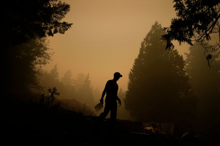 Aaron Cleys holds a jug of water he was using to douse hot spots at a home destroyed by the the Riverside Fire, Friday, Sept. 11, 2020, in Estacada, Ore.