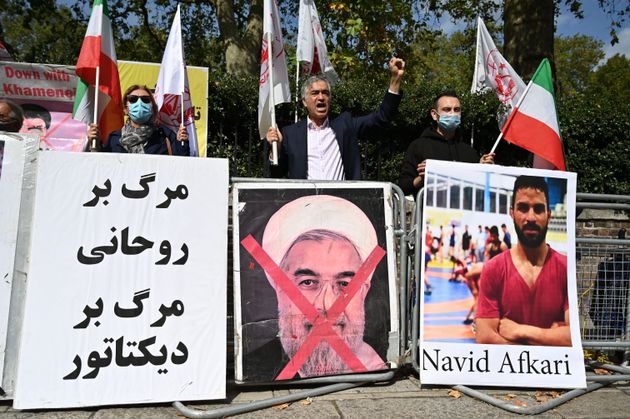 Protesters wave the Lion and Sun flag of the National Resistance Council of Iran and the white flag ...