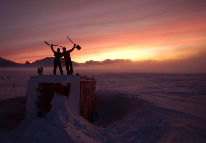 In this handout photo provided by British Antarctic Survey, field guides Sarah Crowsley, left, and Sam Hunt, right, pose for a photo after digging out the caboose, a container used for accommodation that can be moved by a tractor, at Adelaide island, in Antarctica on Friday, June 19, 2020. 