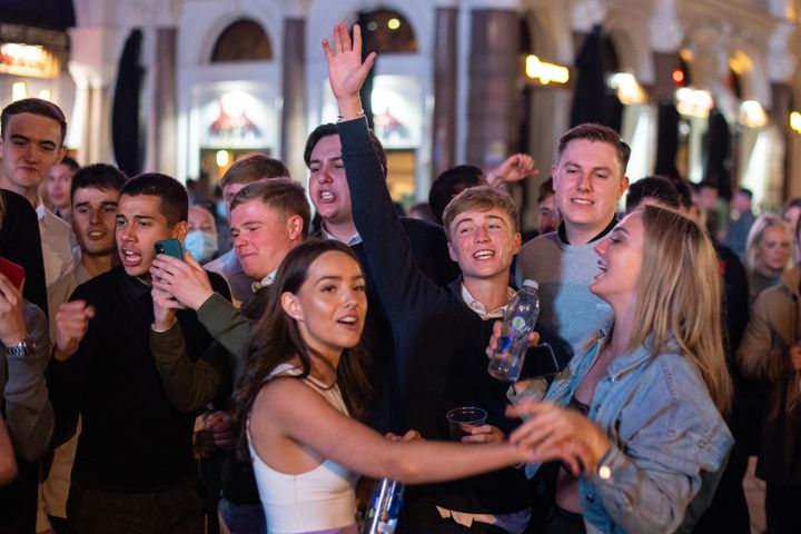 People sing and dance as they watch a street performer in Leicester Square, in London's West End before rule of six restrictions come into force