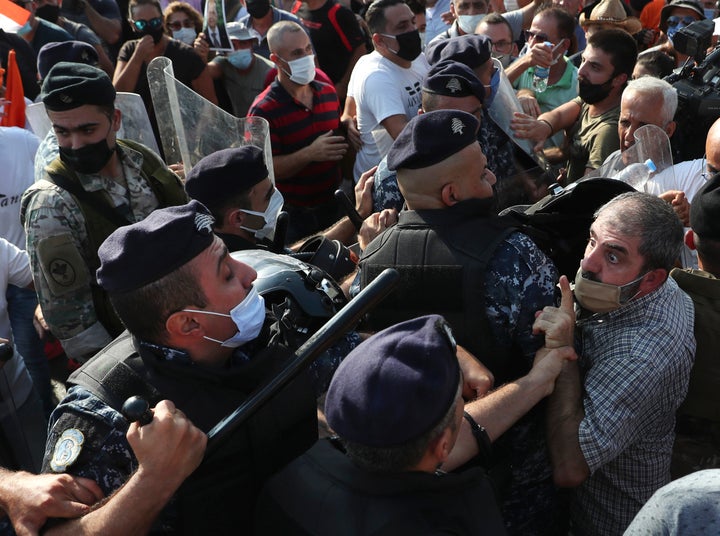 A supporter of Lebanese President Michel Aoun argues with riot police as they try to take a main road that links to the presi