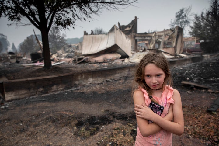 Ellie Owens, 8, from Grants Pass, Ore., looks at fire damage Friday, Sept. 11, 2020, as destructive wildfires devastate the region in Talent, Ore. (AP Photo/Paula Bronstein)