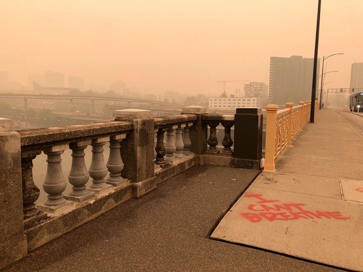 A graffiti sign reads, "I Can't Breathe," in heavy smoke from the wildfires creating an orange glow over Portland, Ore., Saturday, Sept. 12, 2020. (AP Photo/Lindsay Whitehurst)