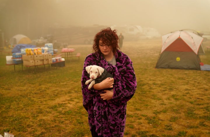 Shayanne Summers holds her dog Toph while wrapped in a blanket after several days of staying in a tent at an evacuation cente