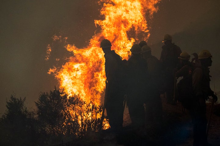 Firefighters monitor a controlled burn along Nacimiento-Fergusson Road to help contain the Dolan Fire near Big Sur, Californi