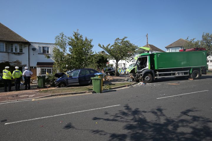 Police at the scene of a collision in Broad Walk, Kidbrooke, south-east London, where the driver of a lorry which hit two cars before crashing into a house died and an 11-year-old child is in a life-threatening condition in hospital.