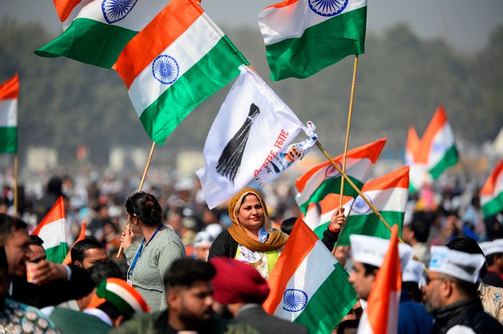 Supporters of the Aam Aadmi Party (AAP) hold party flags and Indian national flags before Arvind Kejriwal swearing-in ceremony as Delhi Chief Minister, in New Delhi on February 16, 2020. 