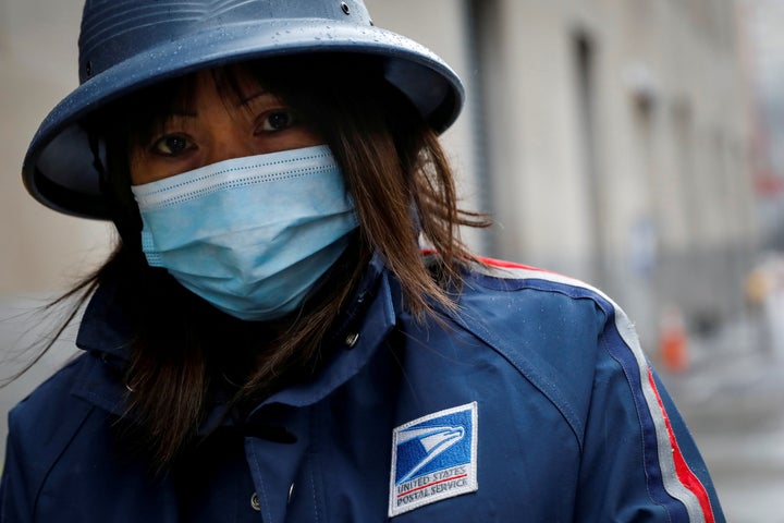 A USPS employee works in the rain in Manhattan during the outbreak of the coronavirus in New York City on April 13, 2020. 