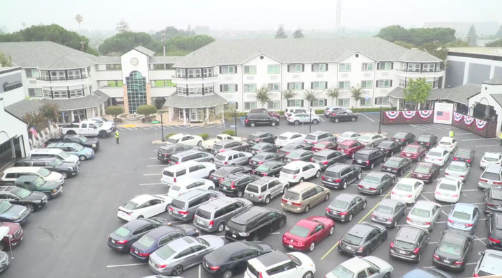 After weeks of holding indoor services that violated local health orders, parishioners gather in a parking lot to attend a se