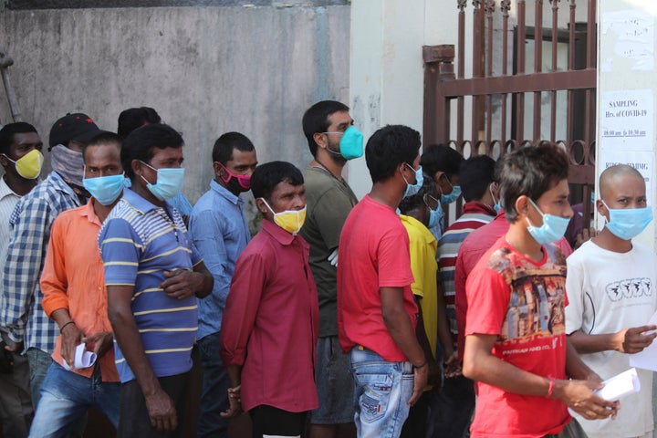 People wait in line to receive COVID-19 tests at a government hospital in Jammu, India on Tuesday.