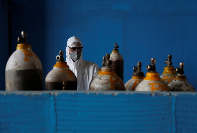 A medical worker stands next to an oxygen cylinder at the Yatharth Hospital in Noida, on the outskirts...
