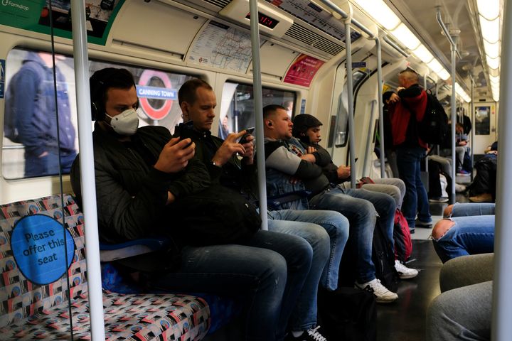 Commuters, some wearing protective masks to protect against coronavirus travel on a Jubilee Line underground train, in London